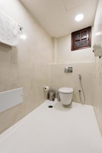 a white bathroom with a toilet and a sink at Eva Mare Hotel & Suites - Adults only in Agia Pelagia