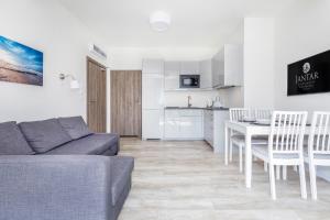 a living room with a couch and a table and a kitchen at Jantar Apartamenty - 5 Mórz Sianożęty in Sianozety