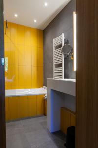 ein Badezimmer mit gelben Wänden, einer Badewanne und einem Waschbecken in der Unterkunft Logis Hotel Restaurant La Tour in Dunières
