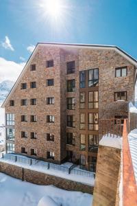 un grand bâtiment en briques avec le soleil au ciel dans l'établissement Pierre & Vacances Pas de la Casa Princesa, au Pas de la Case