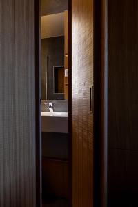 ein Bad mit einem Waschbecken und einem Spiegel in der Unterkunft Logis Hotel Restaurant La Tour in Dunières