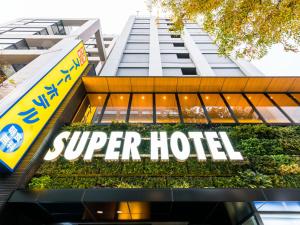 Super Hotel Tokyo Kinshicho Ekimae في طوكيو: علامة فندق ممتازة أمام مبنى طويل