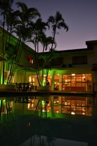 a building with palm trees and a pool at night at Premier Splendid Inn Pinetown in Pinetown
