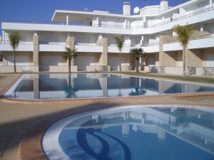 a swimming pool in front of a building at Apartamentos Pomba Branca in Olhos de Água