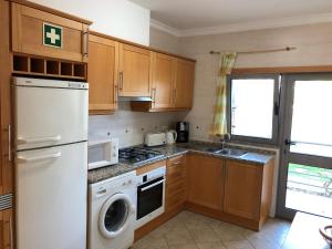 a kitchen with a white refrigerator and a dishwasher at Apartamentos Pomba Branca in Olhos de Água