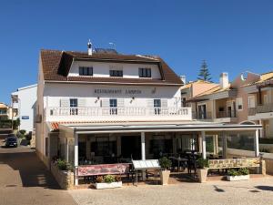 a white building with a table and chairs in front of it at Apartamentos Pomba Branca in Olhos de Água