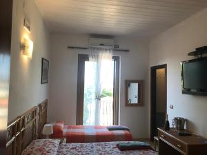 una camera con due letti, una televisione e una finestra di Casa Elvira a Isola Capo Rizzuto