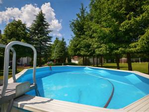 a blue swimming pool with a chair and trees at Quaint Holiday Home in Domaslawice with Swimming Pool in Darłowo