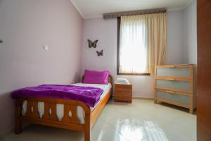 カヴァラにあるOldtown Apartmentのベッドルーム1室(紫のシーツが敷かれたベッド1台、窓付)