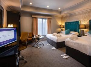 a hotel room with two beds and a flat screen tv at Treacys Oakwood Hotel in Shannon