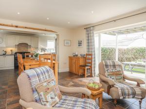 a living room with two chairs and a kitchen at Curragho in Trearddur