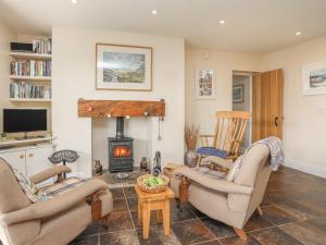 a living room with two chairs and a fireplace at Curragho in Trearddur