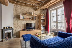 salon z 2 niebieskimi krzesłami i telewizorem w obiekcie Veeve - Saint-Louis Style w Paryżu