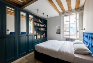 a bedroom with a bed with blue cabinets and a window at Veeve - Saint-Louis Style in Paris