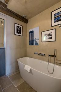 a white bath tub in a bathroom with pictures on the wall at Veeve - Saint-Louis Style in Paris