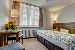 a hotel room with a bed and a table with flowers on it at Hotel Książ in Wałbrzych +159 photos