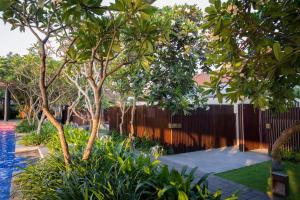 a garden with trees and a fence and a pool at The Anvaya Beach Resort Bali in Kuta