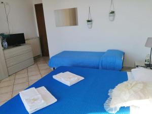 two beds in a room with blue sheets and towels at I Cardinali in Santa Marinella