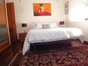 1 dormitorio con 1 cama con una pintura en la pared en Orchidea Terrace, en Malveira da Serra