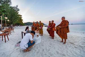 a group of people in orange robes standing on a beach at AKIRA Lipe Resort in Ko Lipe