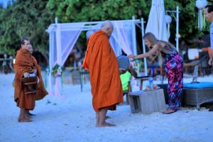 a group of people standing on a beach with a monk at AKIRA Lipe Resort in Ko Lipe