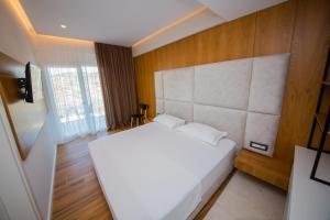 a bedroom with a white bed and a large window at Inada Hotel Ksamil in Ksamil