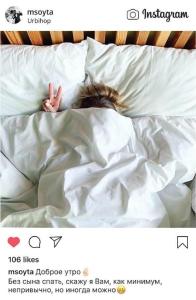 une personne dormant dans un lit avec des draps blancs dans l'établissement Urbihop Hotel, à Vilnius