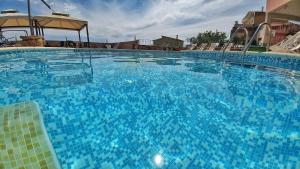 een groot blauw zwembad met stoelen en een parasol bij Hotel Meridiana in Arbus