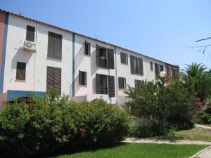 un bâtiment blanc avec des fenêtres et des buissons à volets noirs dans l'établissement Estrela Mar Marina Villa, à Quarteira