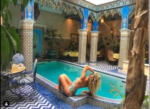 une femme qui se couche dans une piscine dans une maison dans l'établissement Riad Puchka, à Marrakech