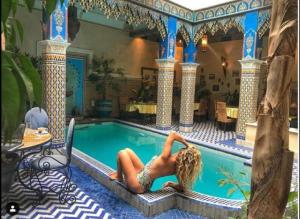a woman in a bikini sitting in a swimming pool at Riad Puchka in Marrakesh