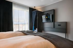 a bedroom with a bed with a tv on the wall at the niu Square in Mannheim