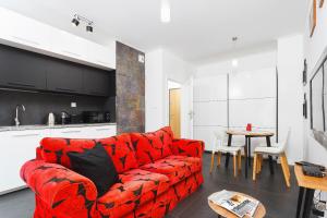 een woonkamer met een rode bank en een tafel bij Apartments GO Rakowicka by Noclegi Renters in Krakau