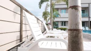 a row of white lounge chairs on the balcony of a building at Aneeda Inn in Pantai Cenang