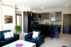 a living room with a couch and a kitchen at Sleek & Cozy Apartment with Pool & Patio In Abdoun in Amman
