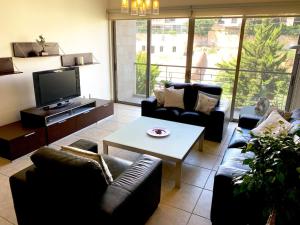 a living room with couches and a table and a tv at Sleek & Cozy Apartment with Pool & Patio In Abdoun in Amman