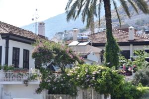 a white house with a palm tree and flowers at Keramos Pansiyon in Finike