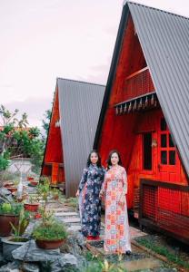duas mulheres em frente a um edifício vermelho em Maison Teahouse homestay em Ha Giang