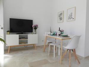 comedor blanco con mesa y TV en BRAND NEW APARTMENT, en Tarifa