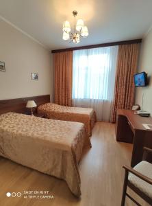 モスクワにあるDerzhavniy Hotelのベッド2台と窓が備わるホテルルームです。