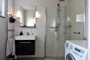 een badkamer met een douche, een wastafel en een wasmachine bij Vakantiehuis Merel in Den Helder