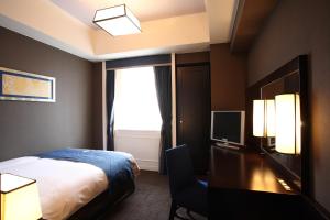 a bedroom with a bed and a television at Hotel Monterey Kyoto in Kyoto