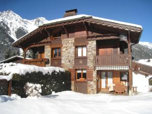 uma cabana de madeira na neve com montanhas em Résidence Chalets Des Bois em Chamonix-Mont-Blanc