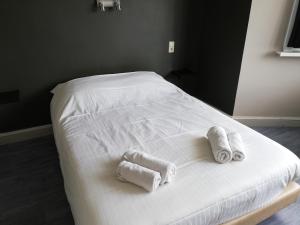 a white bed with three rolled towels on it at Logies Het Maantje in De Panne