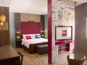 una camera d'albergo con un letto e una TV di Ibis Padang a Padang