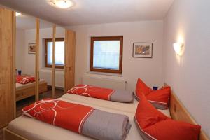 a bedroom with two beds with red pillows and a mirror at Ferienwohnung Krug in Wenns