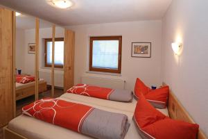 ヴェンスにあるFerienwohnung Krugのベッドルーム1室(赤い枕と鏡付きのベッド2台付)