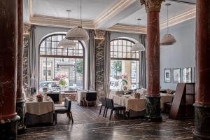 restauracja ze stołami i krzesłami oraz dużymi oknami w obiekcie Hotel Monopol we Wrocławiu