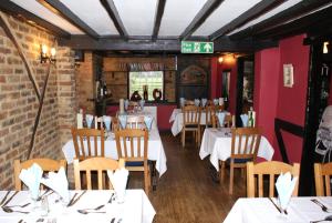 a restaurant with white tables and chairs and a brick wall at The Hawkenbury in Staplehurst