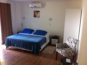um quarto com uma cama com lençóis azuis e uma cadeira em The Hyperion Boutique Hotel em Florianópolis